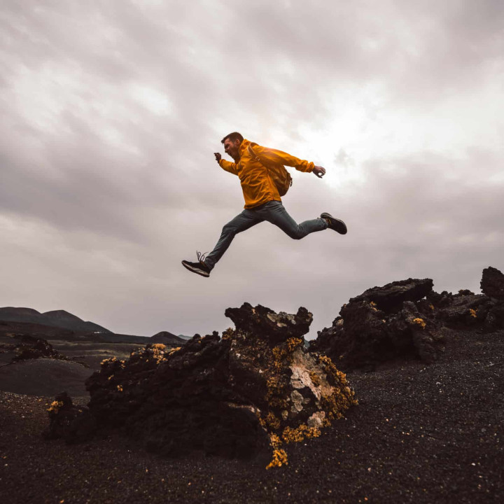 Hiker man jumping over the mountain. Freedom, risk, success and